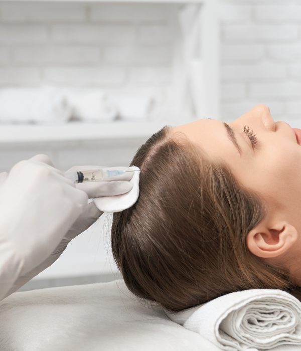 Tratamentos 3 Side view of beautician in white rubber gloves holding injection and doing special procedure for improvements hair for young brunette woman. Concept of beauty procedure in professional salon.